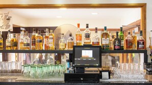 A bar area with various liquor bottles and a digital payment terminal. - The Priory Hotel (Beauly)