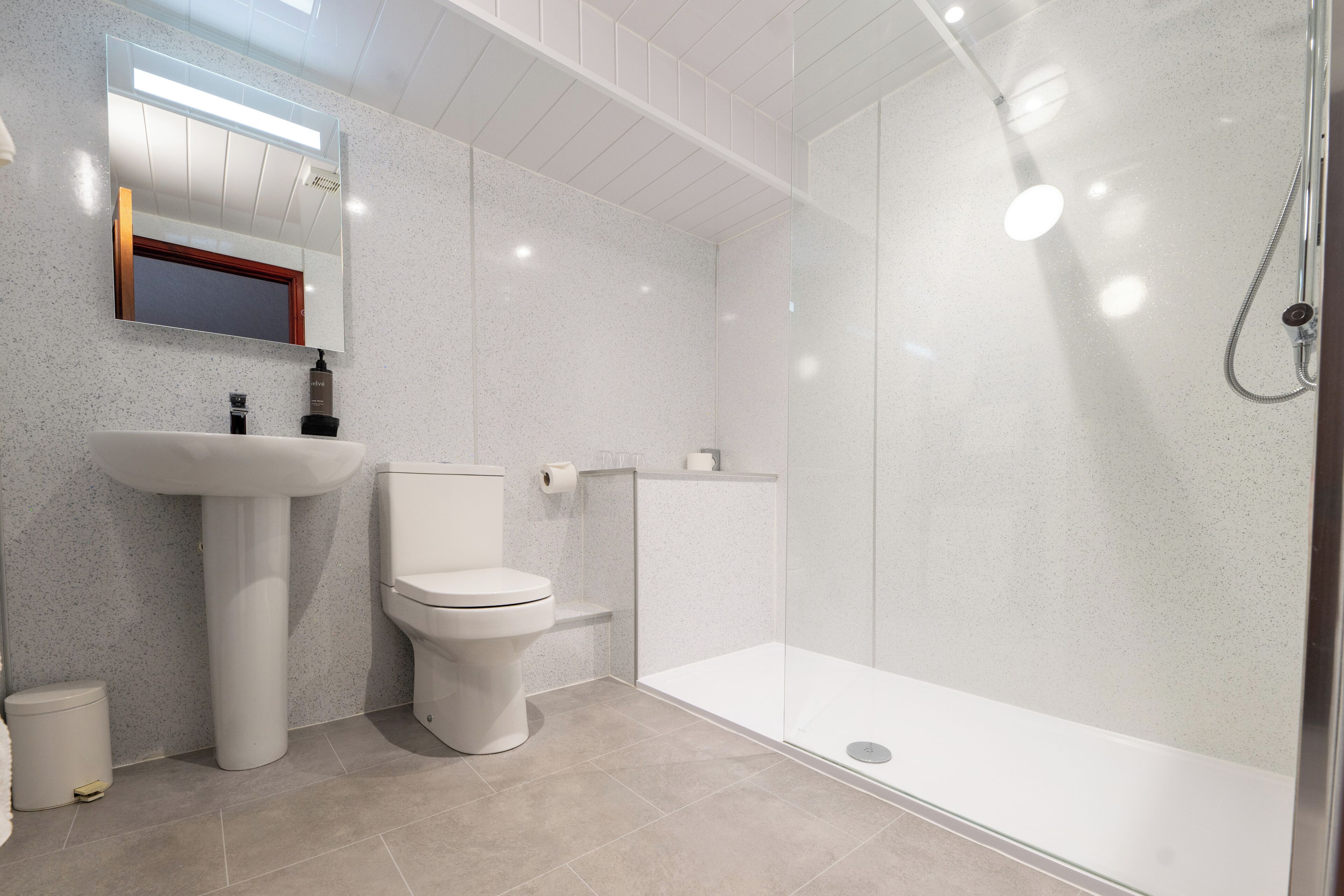 A modern bathroom with a toilet, sink, and glass-enclosed shower.