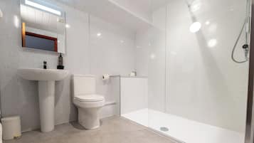 A modern bathroom with a toilet, sink, and glass-enclosed shower.