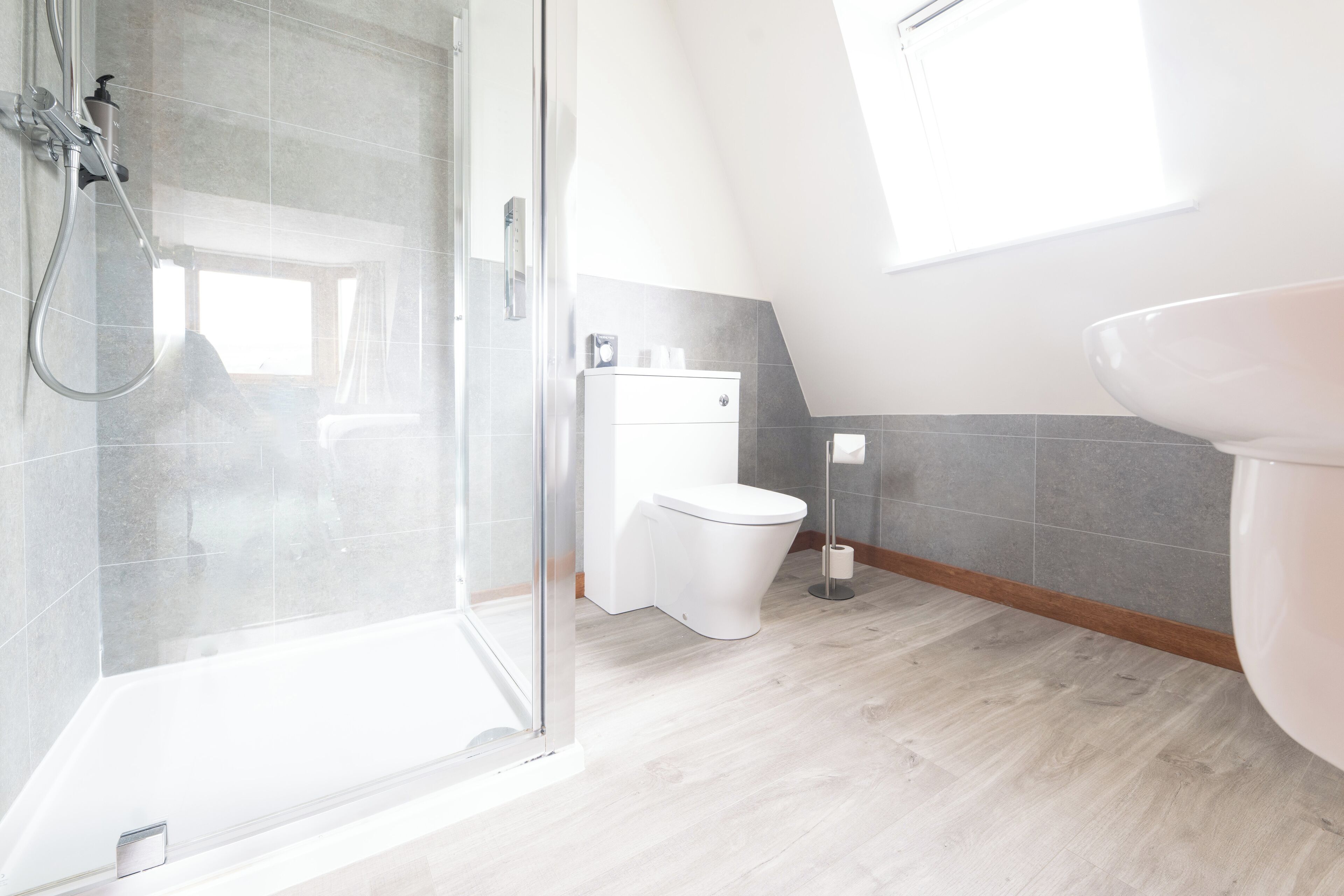 A modern bathroom with a shower, toilet, and sink.