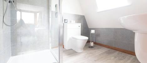A modern bathroom with a shower, toilet, and sink.