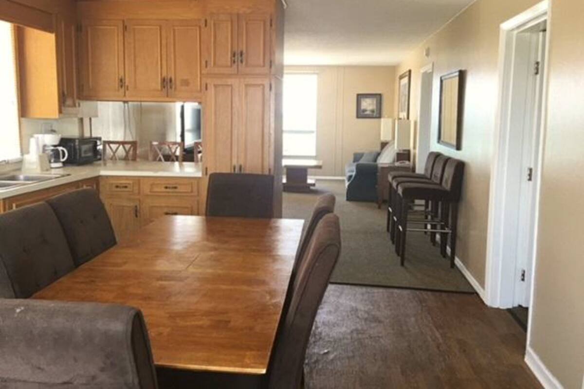 A spacious kitchen with wooden cabinets and a dining area with a large wooden table and chairs.