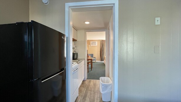 A compact kitchen with a refrigerator, microwave, and a small dining area with a table and chairs. - Polynesian Beach & Golf Resort (Myrtle Beach)