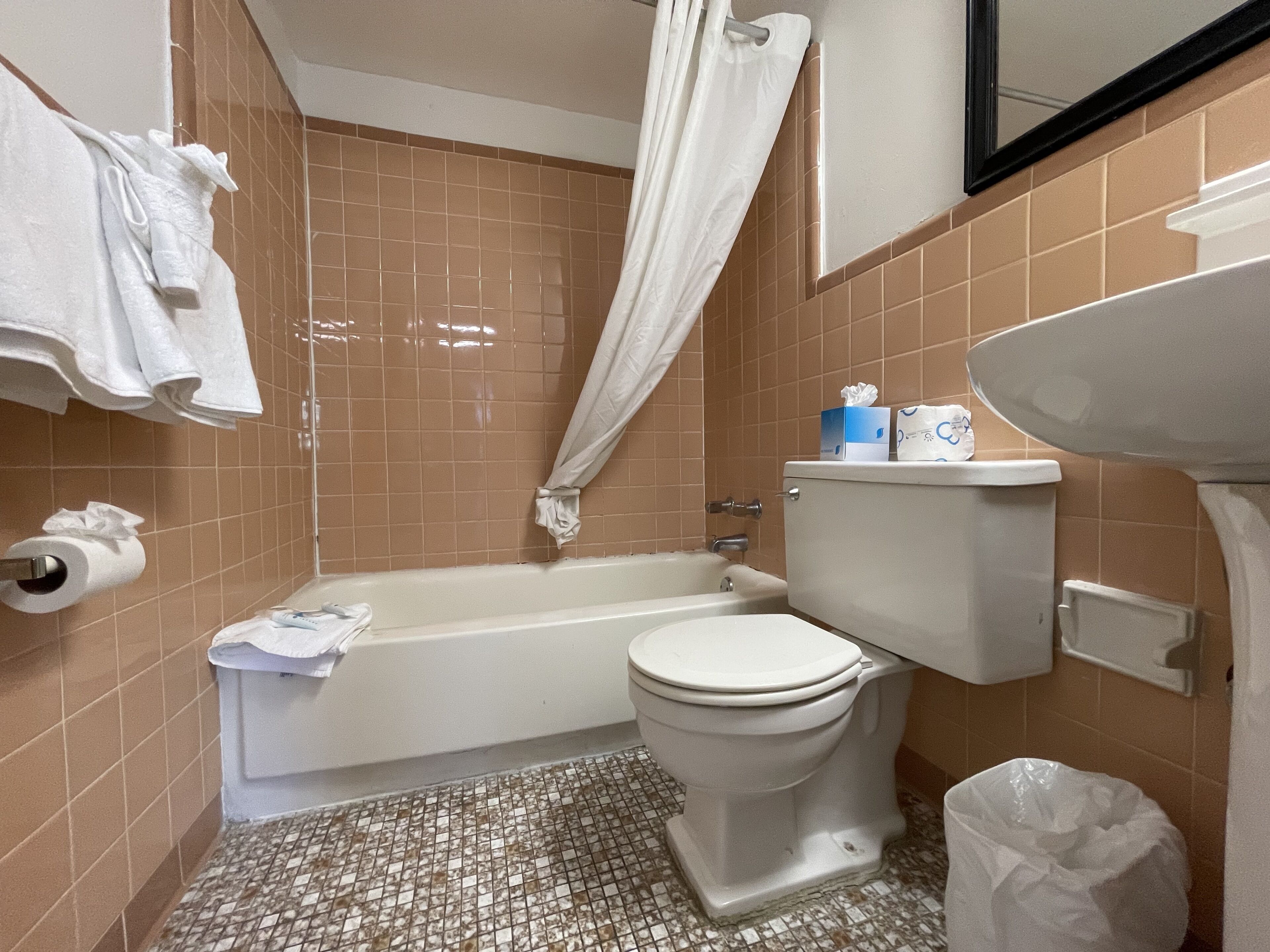 Un baño con bañera, inodoro y lavamanos. Se observan toallas y artículos de aseo.