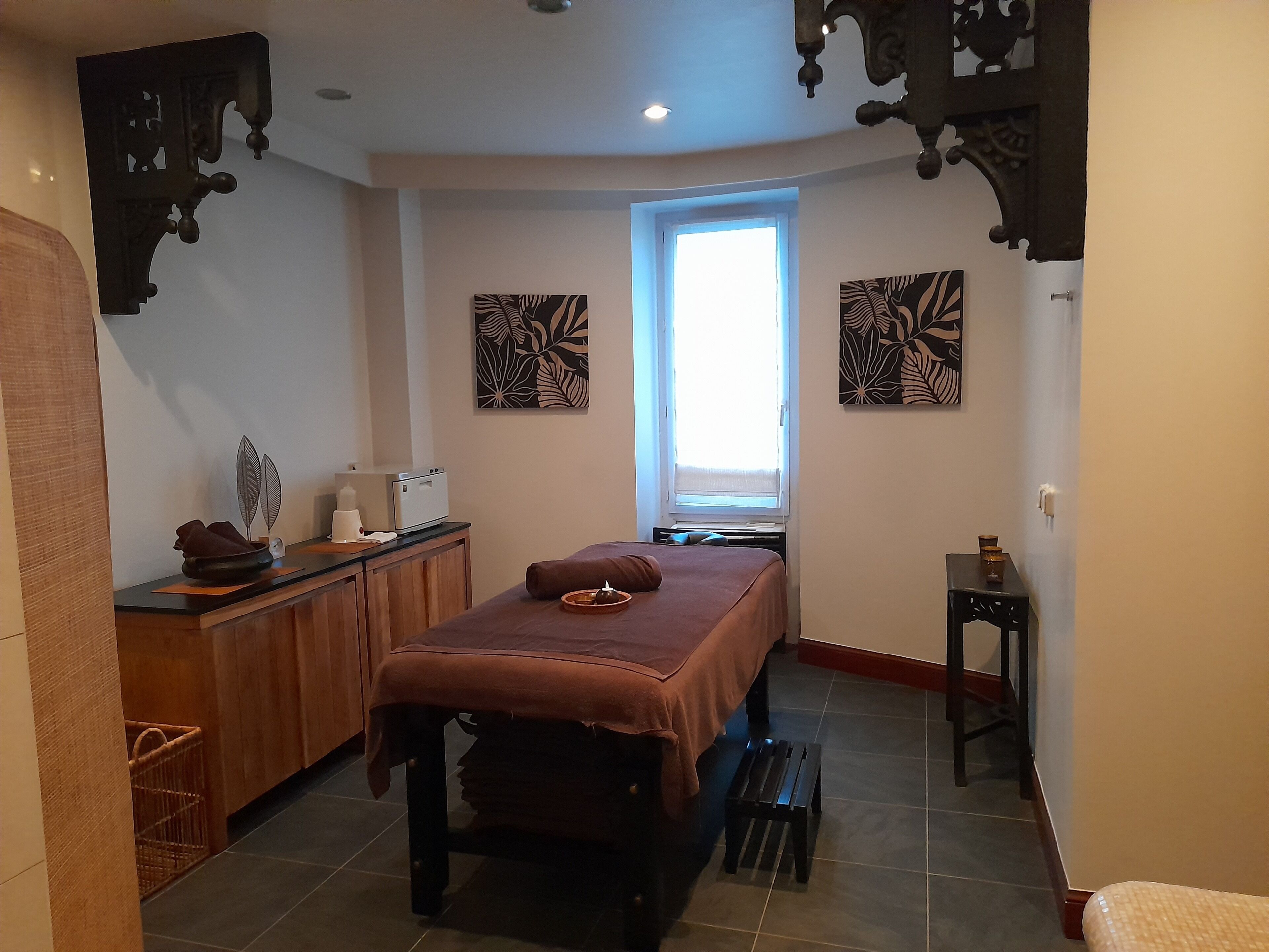 Una habitación con cama, una mesita de noche con lámpara, una ventana y obras de arte en las paredes.