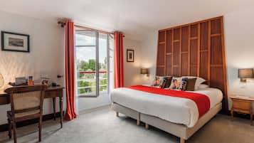 A bedroom with a large bed, a desk, and a window with curtains.