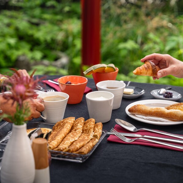 Une table dressée avec des aliments pour le petit-déjeuner, notamment des croissants, une assiette de viennoiseries et des tasses de café.