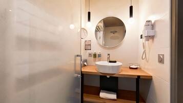 Un baño moderno con un espejo redondo, un lavabo blanco y una encimera de madera.