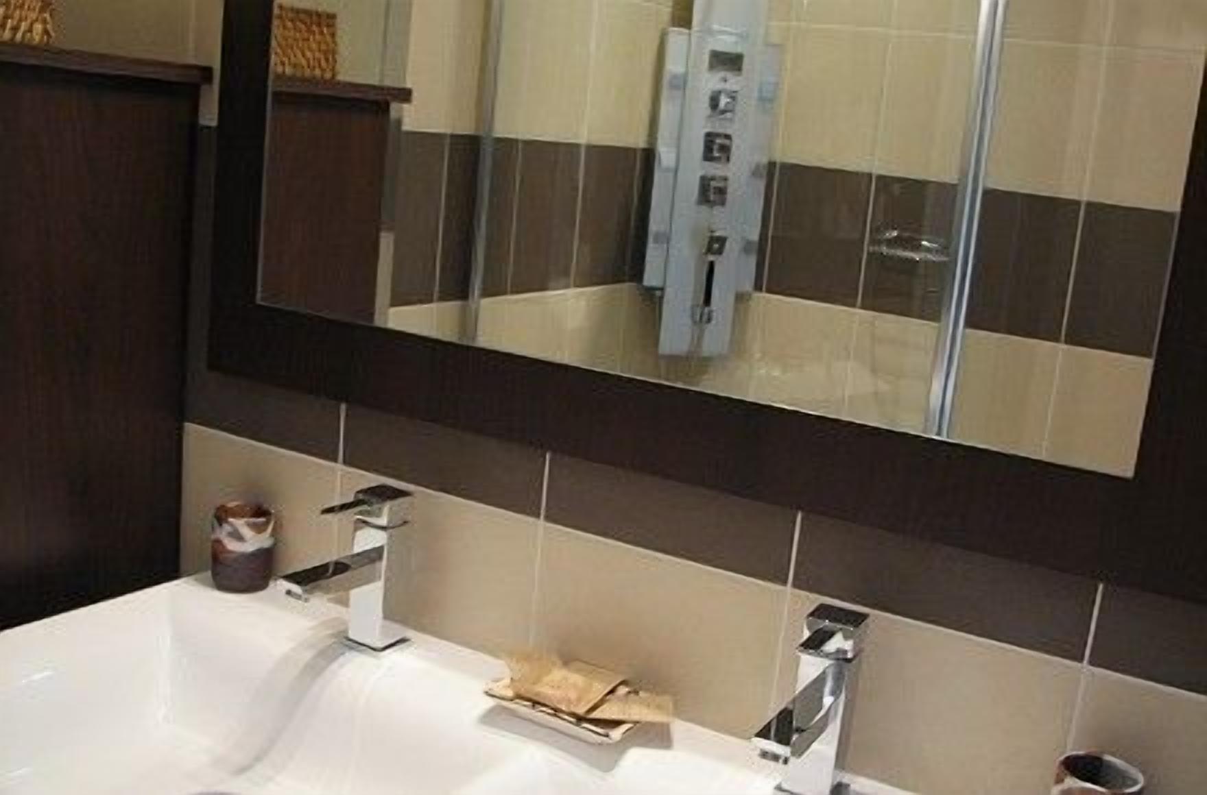 A bathroom with a large mirror, two sinks, and a towel rack.