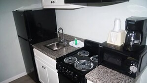 Une cuisine de taille réduite, équipée d’une cuisinière, d’un évier et d’un four à micro-ondes.