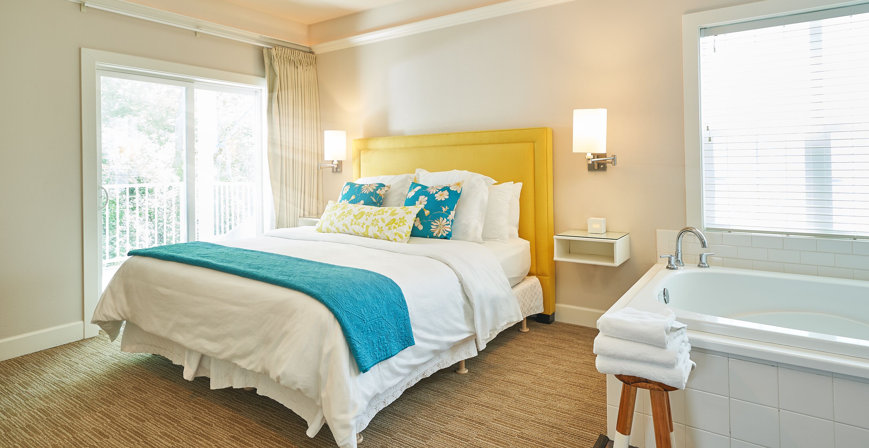 A hotel room with a large bed, a bathroom with a bathtub, and a window with curtains.