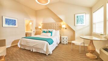 A bedroom with a bed, bedside tables, a round table, and a window with blinds.