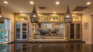 A bar area with a marble countertop, wine bottles, and glasses. There are hanging pendant lights and a 'No Minors' sign. - Lithia Springs Resort (Ashland)