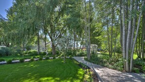 A well-maintained garden with a paved walkway, surrounded by lush greenery and trees. - Lithia Springs Resort (Ashland)