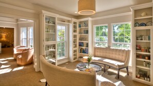 A well-lit room with a sofa, chairs, and a coffee table. There are bookshelves filled with books and decorative items. - Lithia Springs Resort (Ashland)