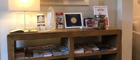 Una consola de madera con revistas y una placa conmemorativa enmarcada.