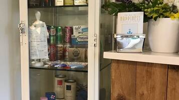Un mueble bar con una variedad de bebidas, incluyendo vino, refrescos y cerveza.