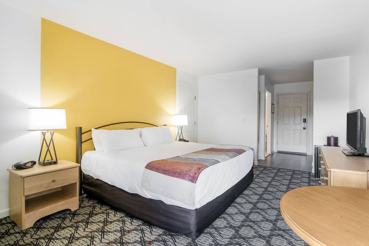 Ein Hotelzimmer mit Bett, Nachttisch, Lampe und Fernseher.