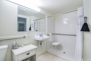 Un baño con lavabo blanco, espejo y zona de ducha.