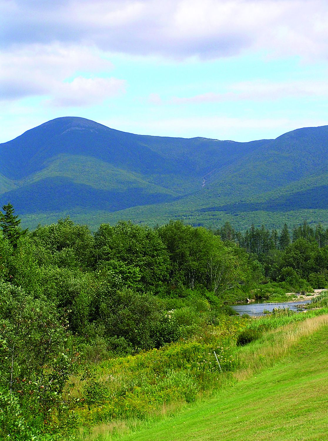 A mountainous landscape with a river and dense greenery.