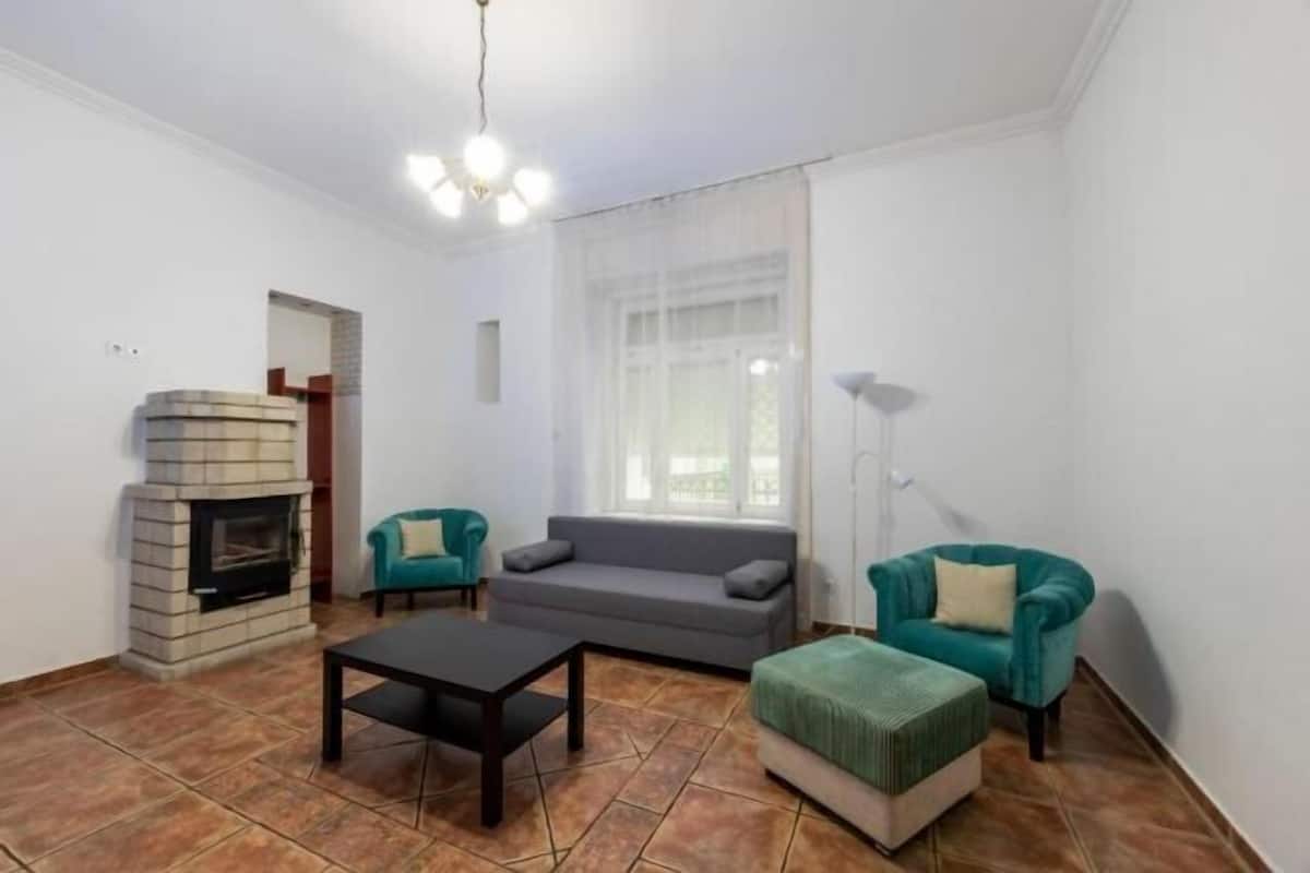 A living room with a fireplace, a sofa, a coffee table, and two armchairs.