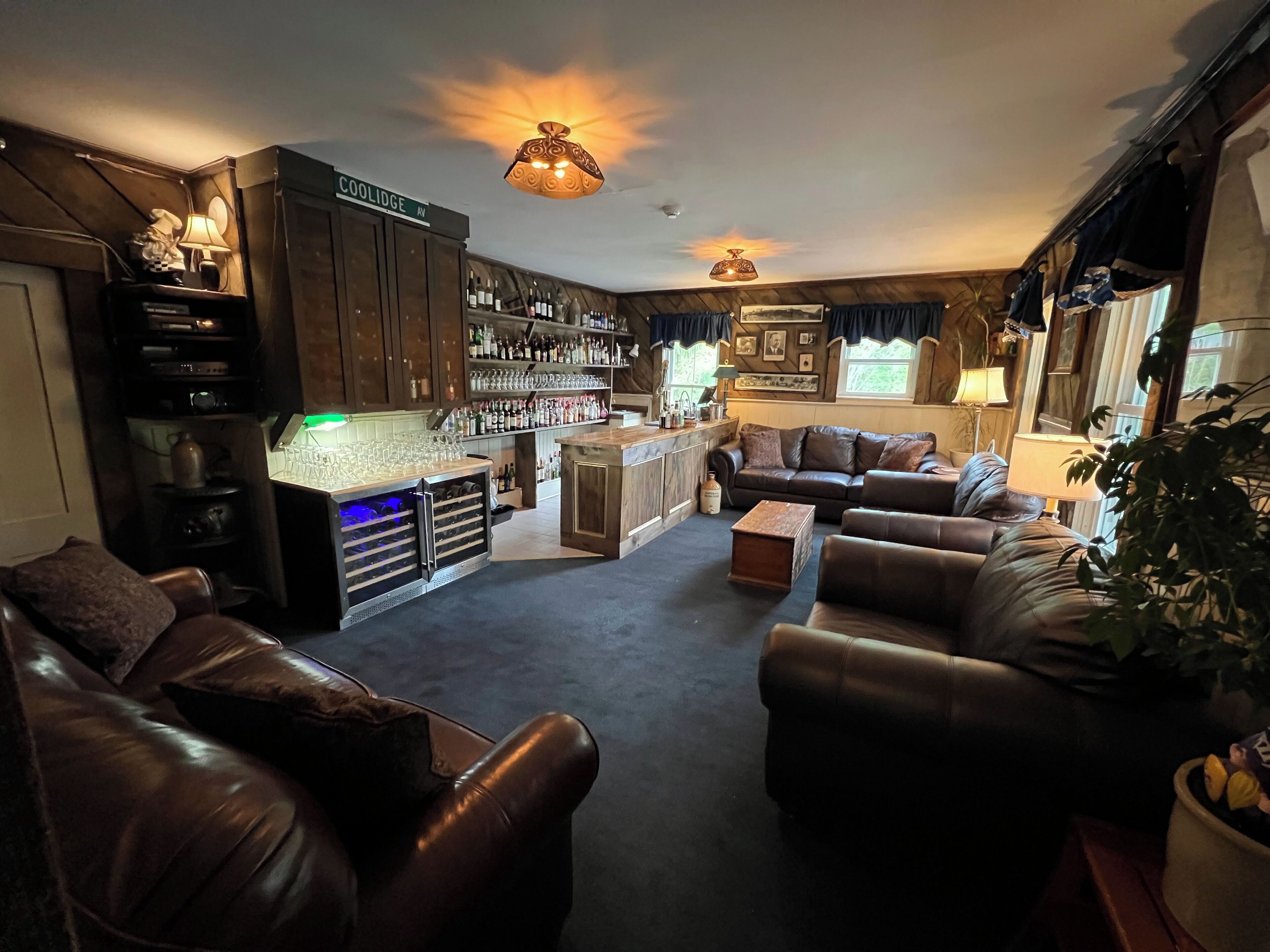 A cozy living room with leather sofas, a bar area with shelves of bottles, and a fireplace.