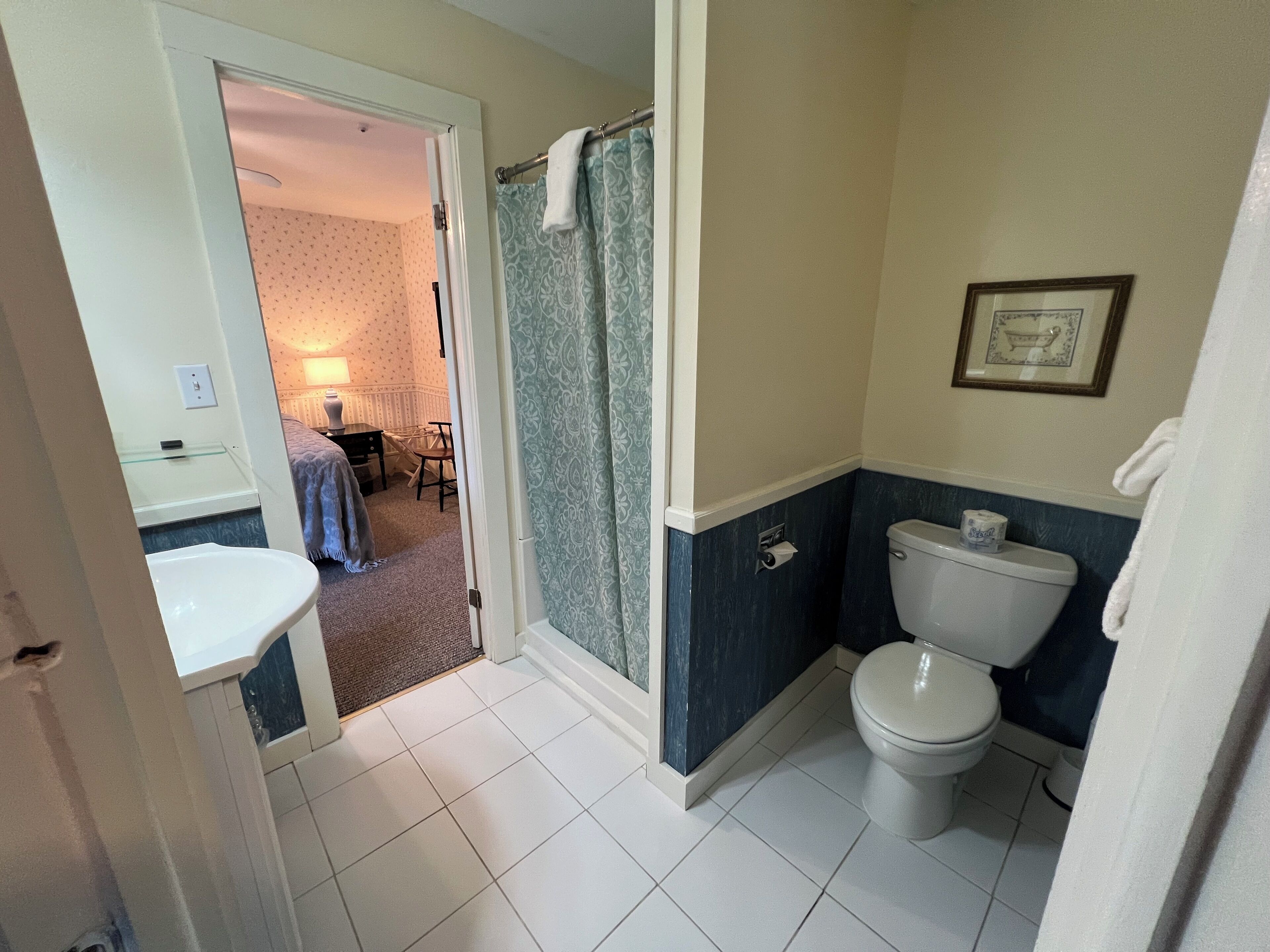 A bathroom with a toilet, a sink, and a shower area.