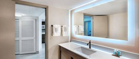 A modern bathroom with a large mirror, a sink, and a towel rack.