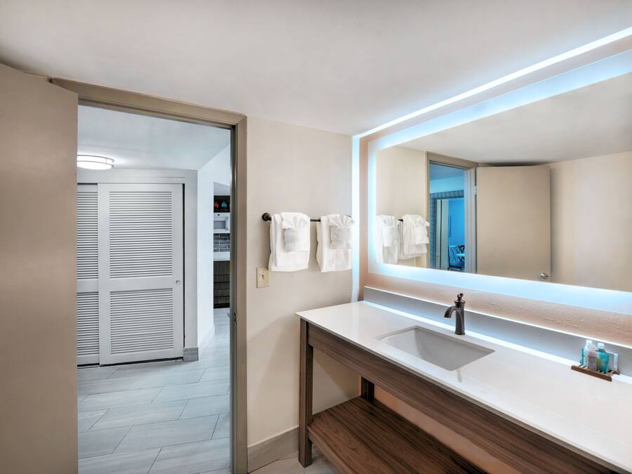 Un baño moderno con un espejo grande, un lavabo y un perchero para toallas.