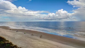 A beach with a clear sky and a few umbrellas. - Bahama House (Daytona Beach Shores)