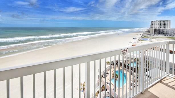 A beach view from a balcony with a pool and lounge chairs. - Bahama House (Daytona Beach Shores)