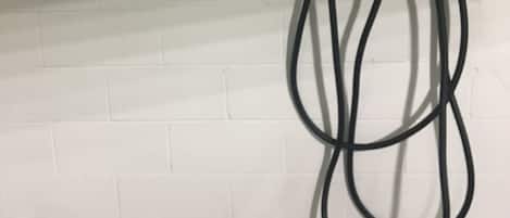 Señal de estacionamiento que indica 'NO ESTACIONAR EXCEPTO DURANTE LA CARGA' y una estación de carga con cables.