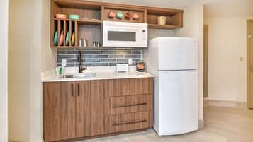 Una cocina con armarios de madera, un microondas blanco, un refrigerador blanco y un salpicadero de azulejos.