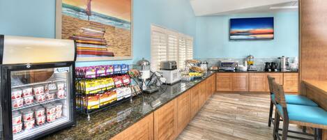 A kitchen area with a refrigerator, microwave, and coffee maker. There are wooden cabinets and a counter with various items.