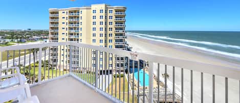 A balcony with a view of a beach and a pool area.