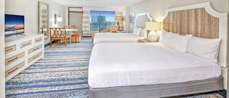 A hotel room with two beds, a desk, a chair, a TV, and a large window with a city view.