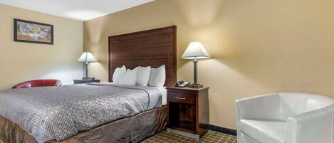 A hotel room with a bed, two bedside tables, a chair, and a wall map.
