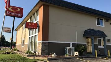 Un edificio su due piani con facciata beige e marrone, un cartello che indica 'EconoLodge' e indicazioni per la reception e l'ingresso.