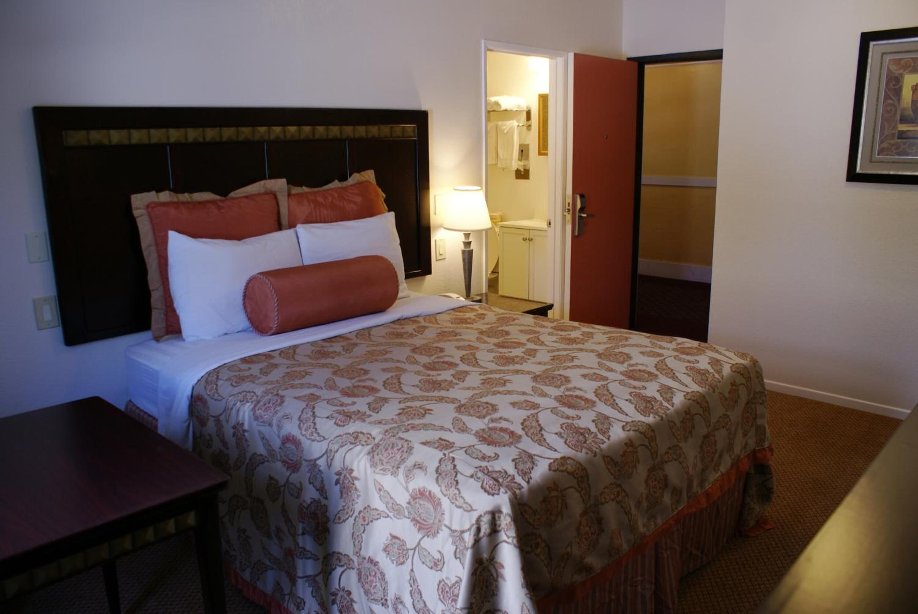 Ein Hotelzimmer mit einem großen Bett, einem Nachttisch, einer Lampe und einem Kleiderschrank.