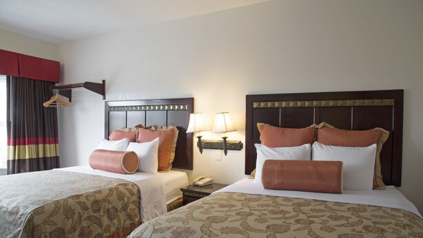 Une chambre d’hôtel avec deux lits, chacun doté d’une tête de lit, de lampes de chevet et d’un téléphone sur la table de chevet.