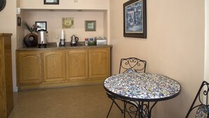 Une cuisine avec des meubles de rangement en bois, un coin café et une table ronde avec des chaises.