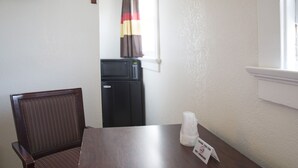 Un petit coin repas avec une table en bois foncé, une seule chaise et un réfrigérateur à l’arrière-plan.