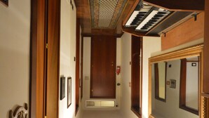 A narrow hallway with wooden paneling, a piano, and large mirrors on the walls. - Hotel Alexis (Rome)