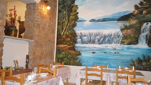 A restaurant with tables set for dining, a mural of a waterfall, and stone walls. - Hotel Alexis (Rome)