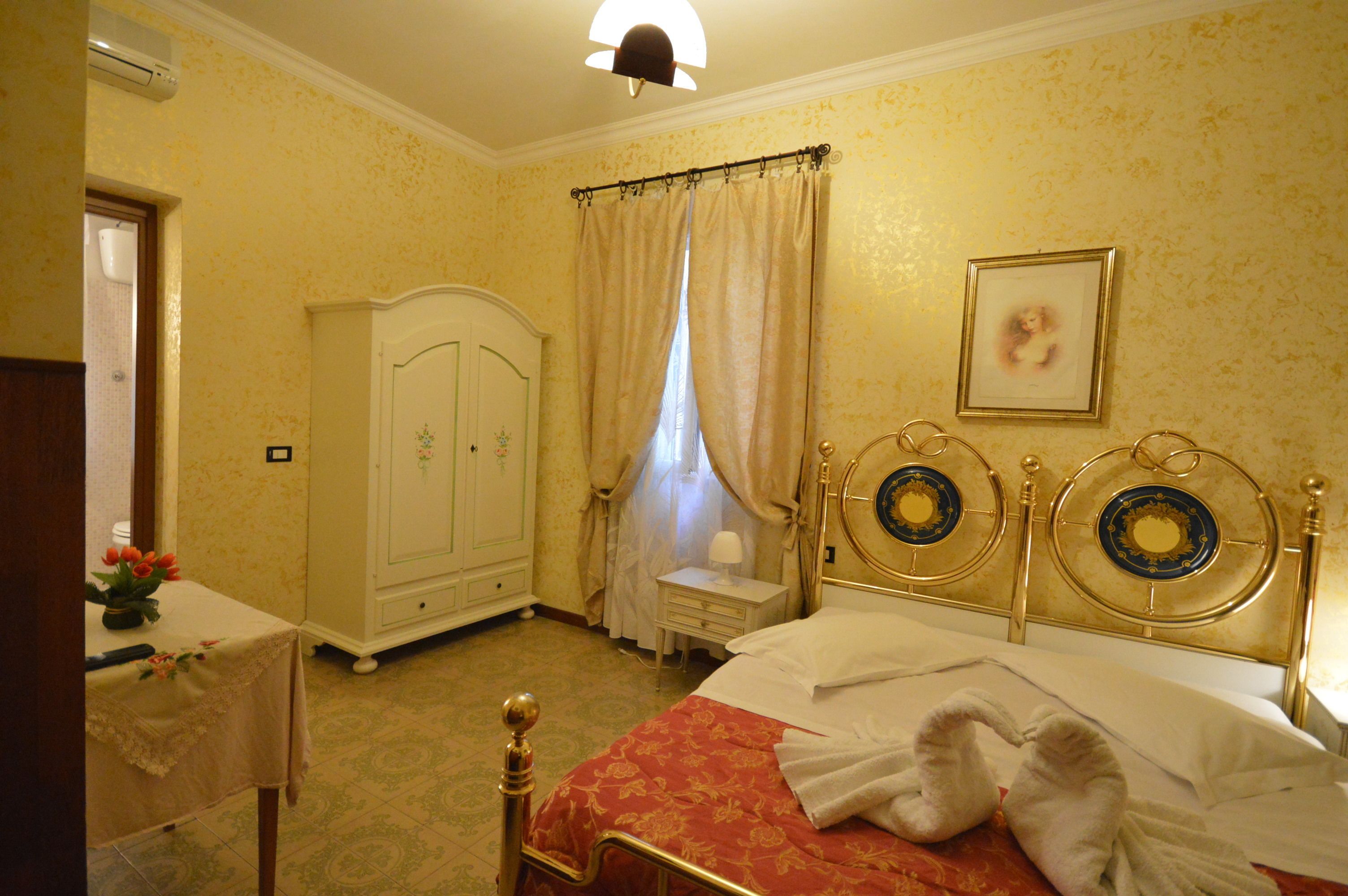 A hotel room with a bed, a nightstand, a wardrobe, and a window with curtains.