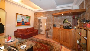 A living room with a red sofa, a wooden cabinet, a gramophone, and a painting on the wall. - Hotel Alexis (Rome)