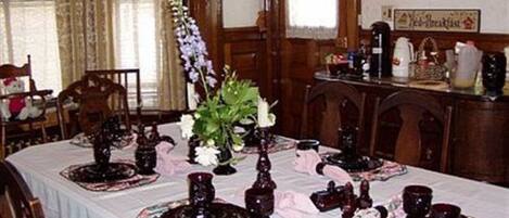 A dining table set with dark glassware, floral centerpieces, and a white tablecloth.