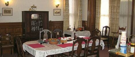 Un comedor con una mesa grande, sillas de madera y un aparador con puertas de cristal.