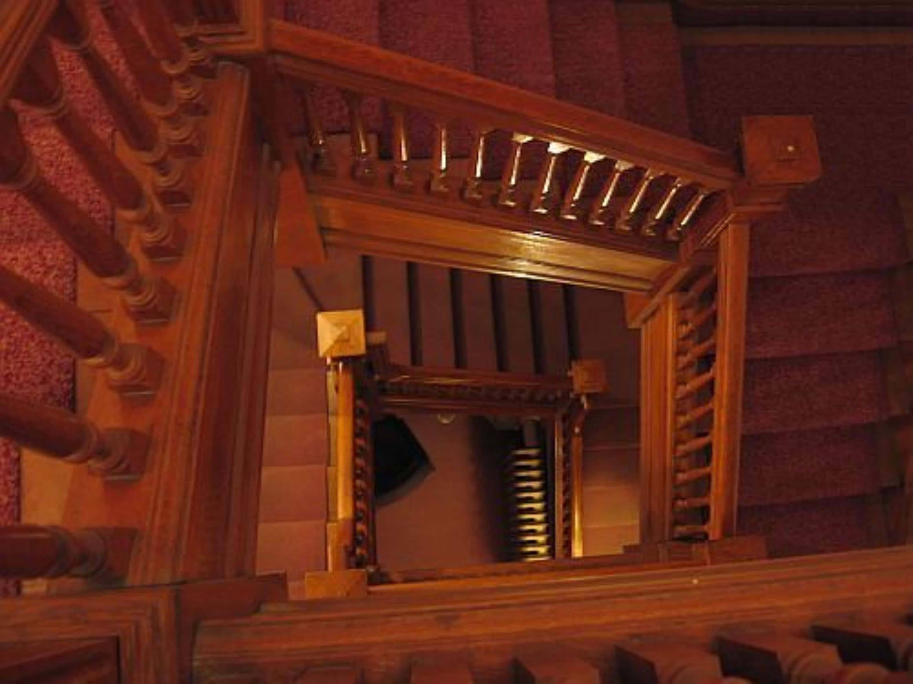 A wooden staircase with a handrail and a wooden frame with a window.