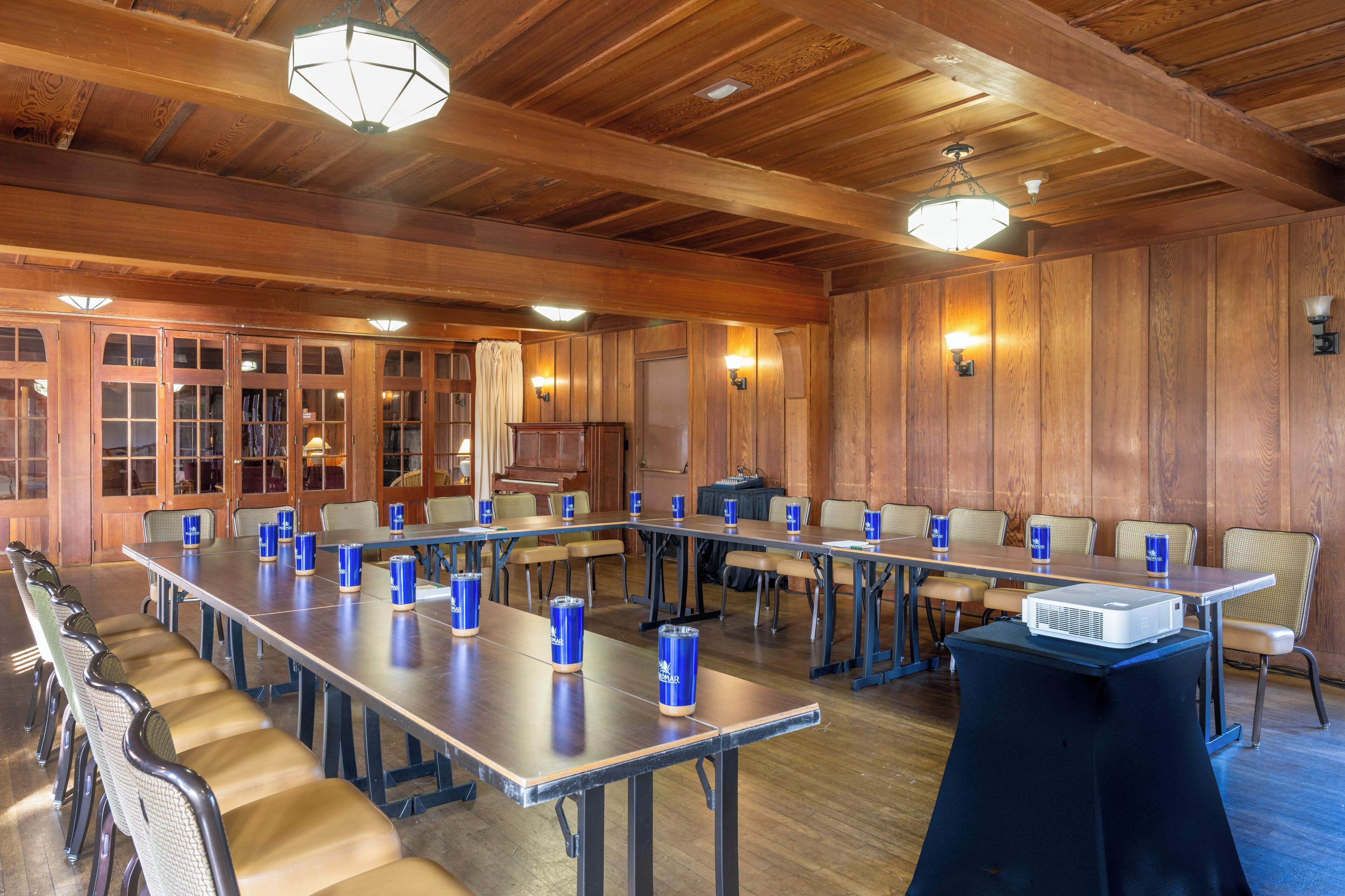 A conference room with long tables, chairs, and a projector on a table.